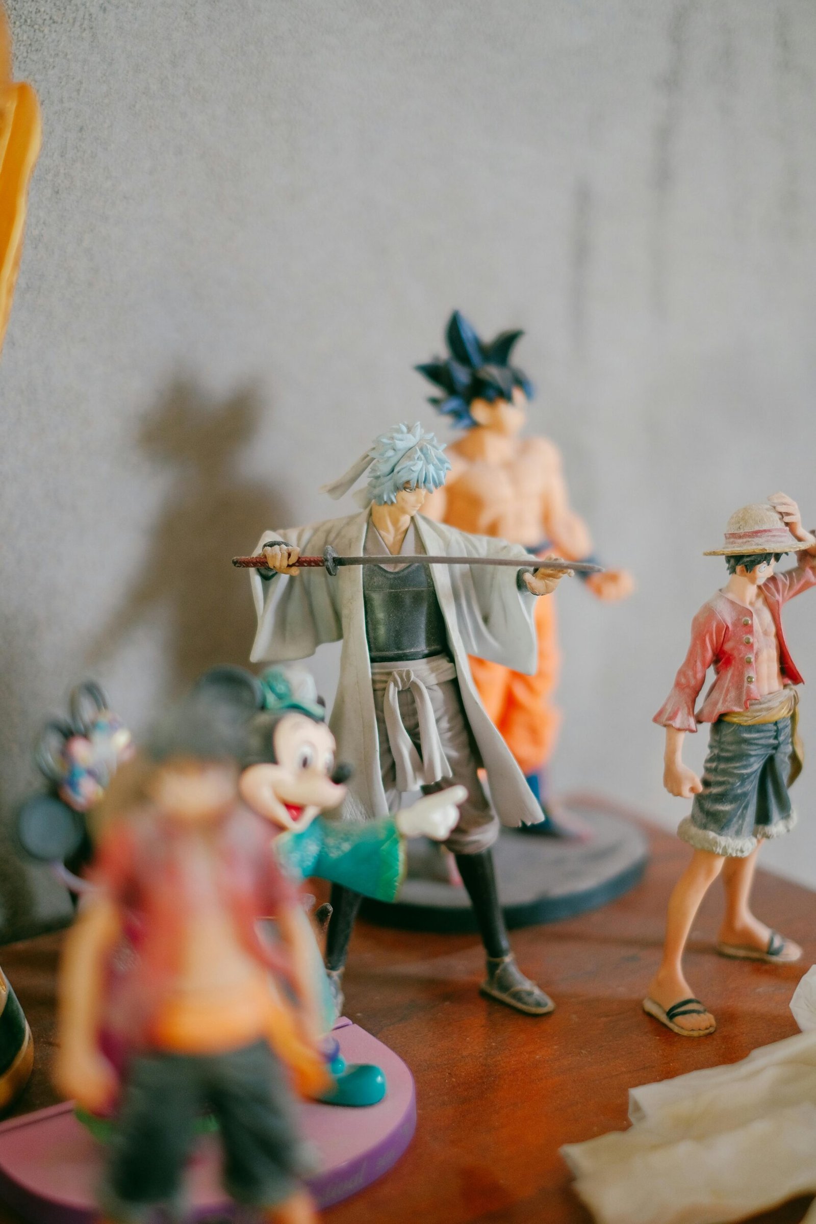 Collection of anime and cartoon figurines on a wooden surface, showcasing popular characters.